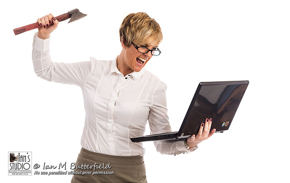 An angry business woman attacks a laptop with an axe