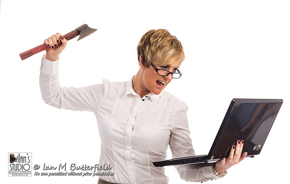 An angry business woman attacks a laptop with an axe