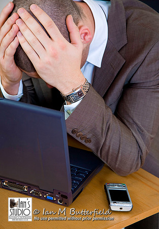 A young businessman sitting at a desk looking worried