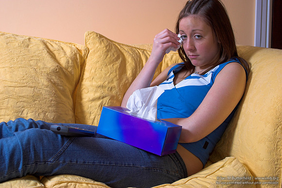 EY0219C-D00744 : Teenage girl sitting on a sofa crying while watching TV