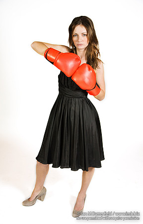 FA0308A-E02268 : A brunette wearing a black evening dress and boxing gloves