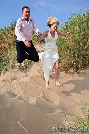 [FB0625E-E03925] Wedding couple jumping in the sand dunes.