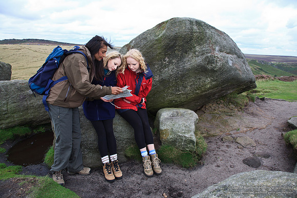 FB0902A-E05252 : Three walkers consult a map while walking on the hills.