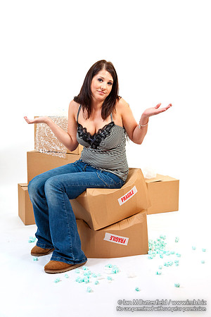 Attractive young woman sitting on storeage boxes marked fragile