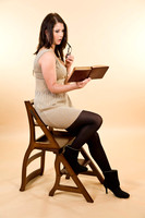 Portrait of a young attractive brunette woman with a book and library chair / steps